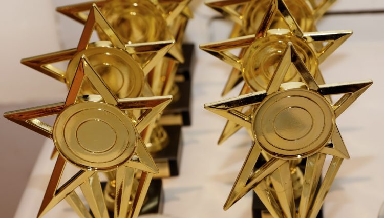 Two rows of golden, star shaped, Rodney Powell Awards.