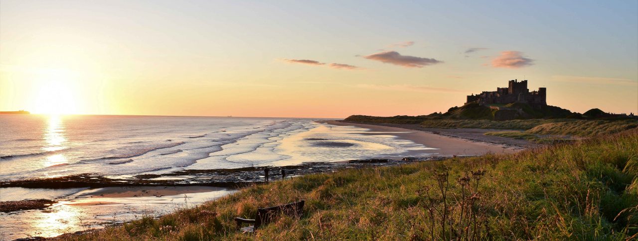 Photo of Bamburgh Castle, taken from the sand dunes on the beach in front of it.