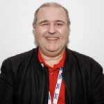 Headshot of Emmanuel Beck, London Sight Loss Council member. Emmanuel is wearing a red polo shirt and black jacket. He is facing the camera, with a big smile on his face,