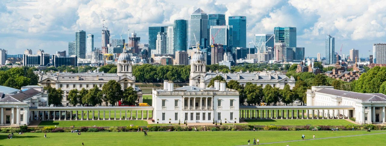 View from the top of the hill at Greenwich Observatory, looking down to the Maritime Museum. Several skyscrapers are shown in the distance at Canary Wharf and the City of London.