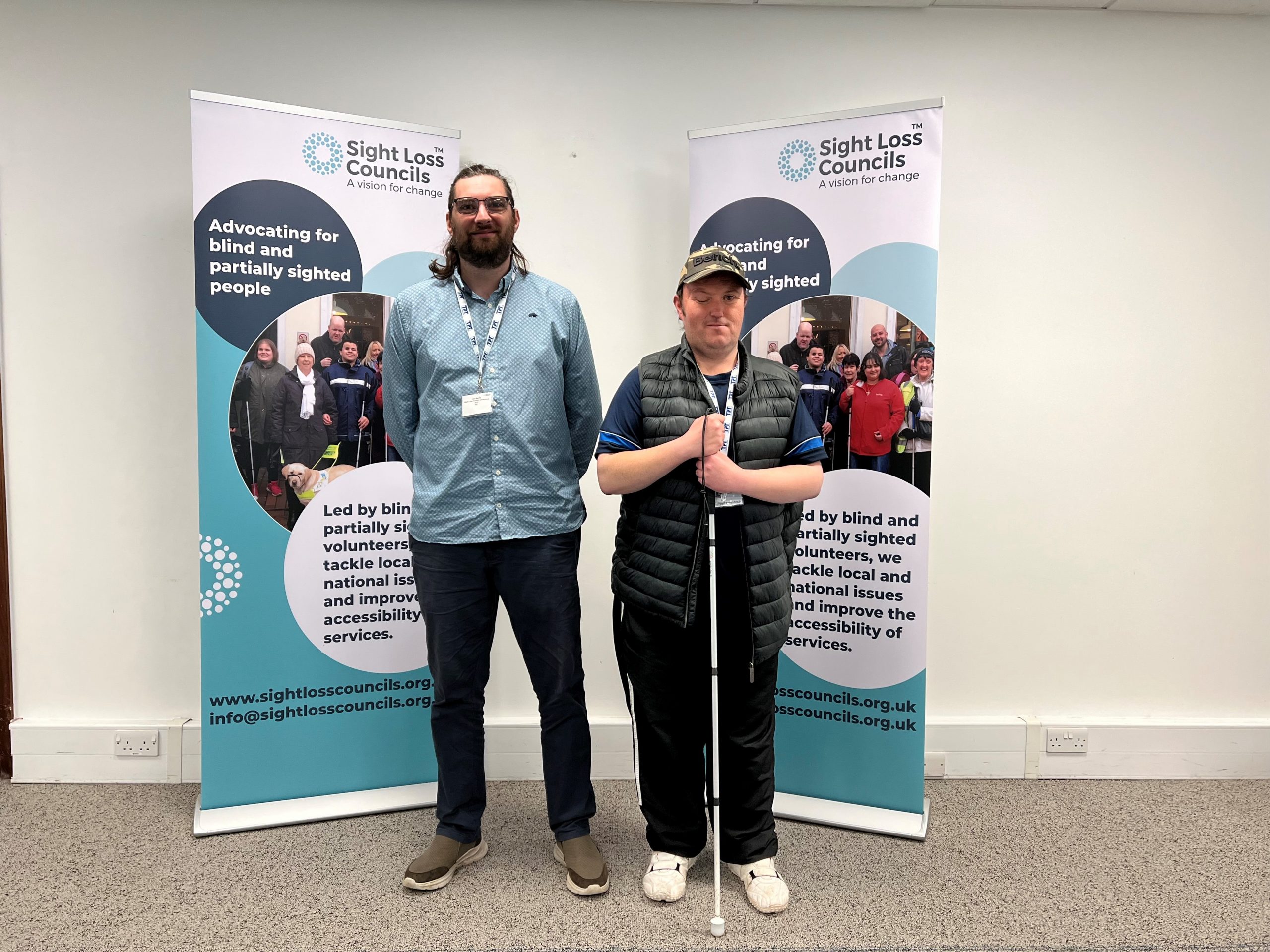 Jack Moffat, Engagement Manager for north east England, with Northumberland SLC member, Matty Bolam. They standing together in front of two SLC banners at the 2023 SLC conference.