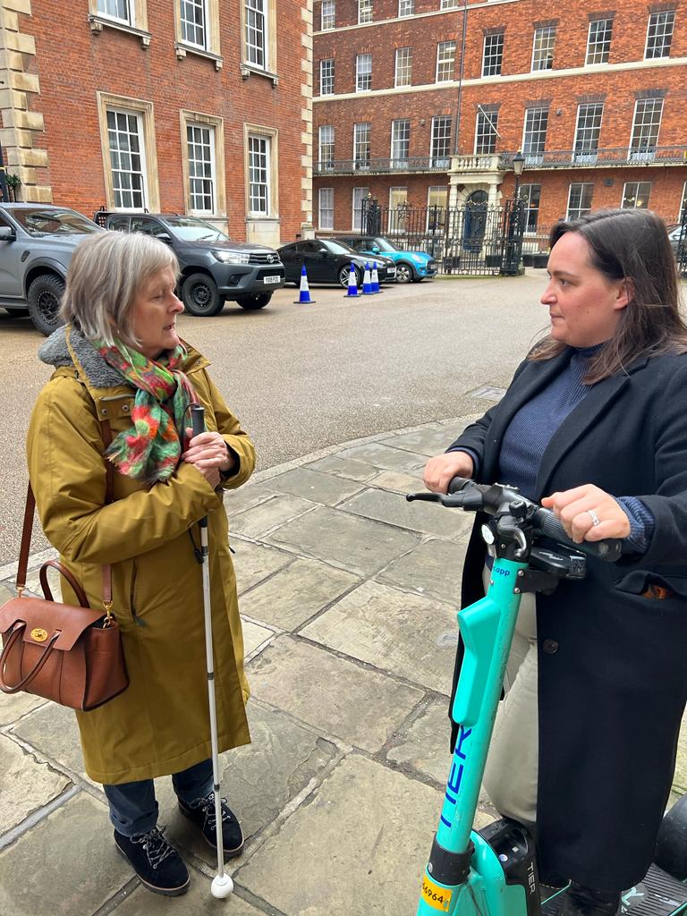 Josie Clarke, North Yorkshire SLC member, is stood talking to Jessica Hall, Head of Public Policy, UK, TIER. Jessica is holding an e-scooter in her hands as they talk.