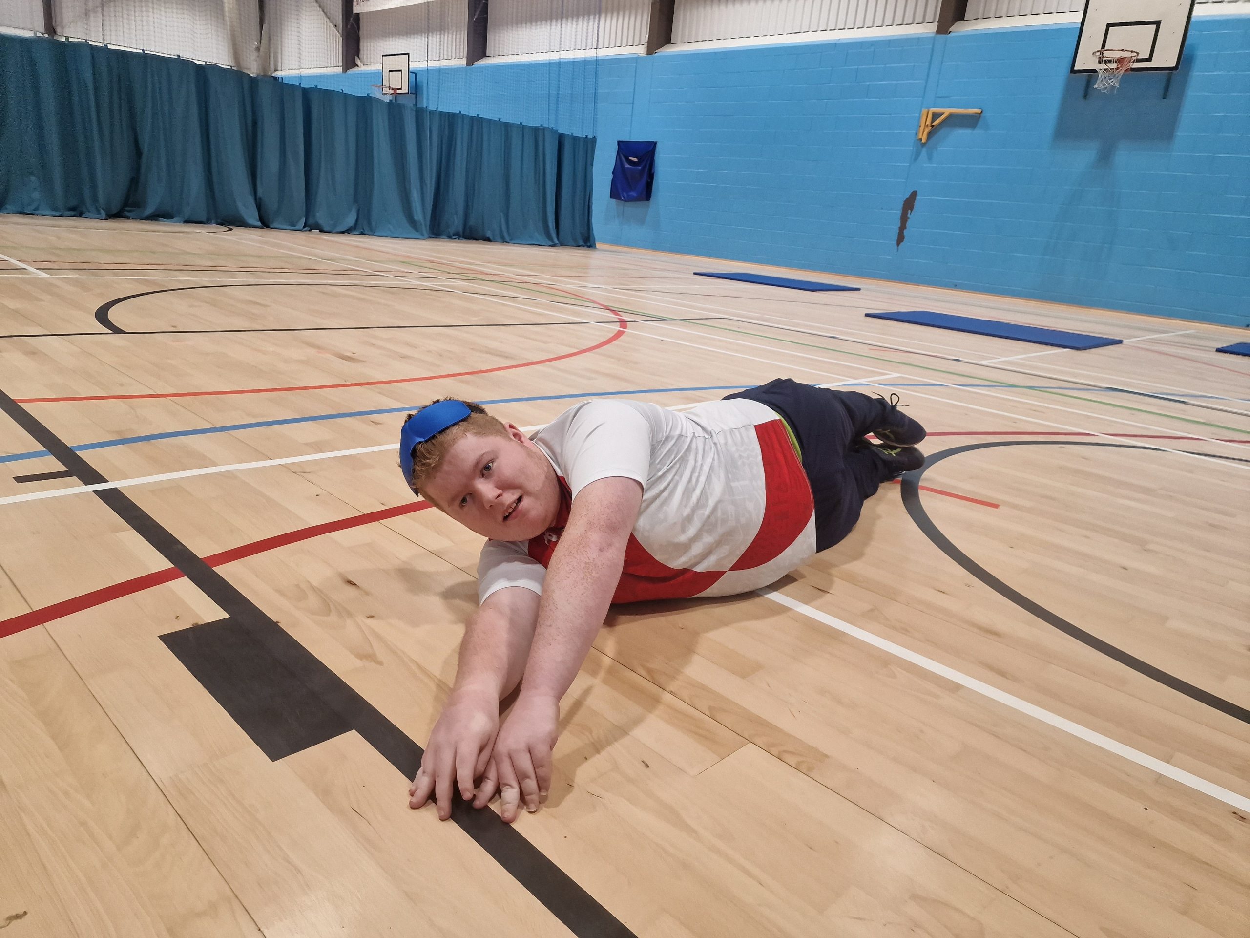 Oliver, 19, poised on ground waiting to catch a ball, in a taster session with Goalball UK