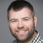 Headshot of Steven reed, London SLC member. He is looking at the camera smiling. he is wearing a navy blue and white checked shirt.