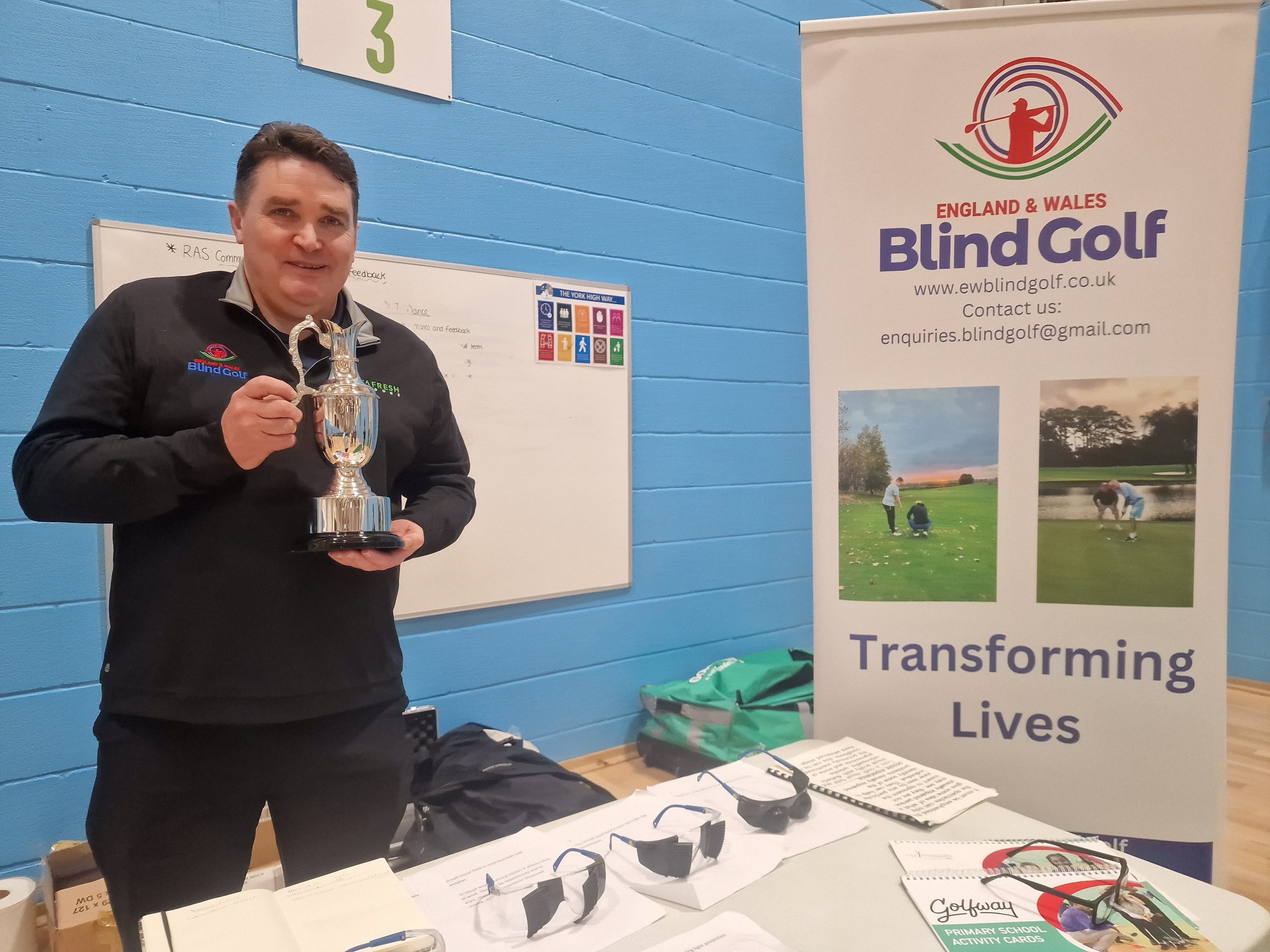 Stuart Hutcheson, British Blind Open Golf champion, and Irish open champion, stood at the British Blind Golf information stall, holding his trophy.