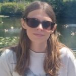 Image of Lauren Eade, South East SLC's coordinator. Lauren is sitting in a garden in the sun. She has long, brown, hair and is wearing sunglasses.