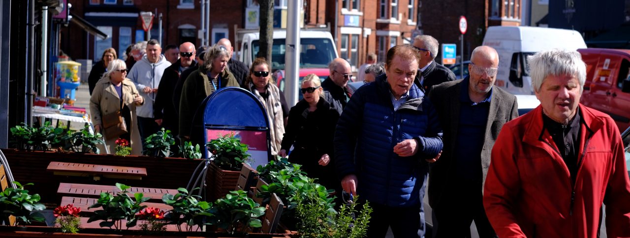 Sefton Council staff members shown during the sim spec walk. They are walking in pairs along a pavement, navigating plant pots and advertising boards.