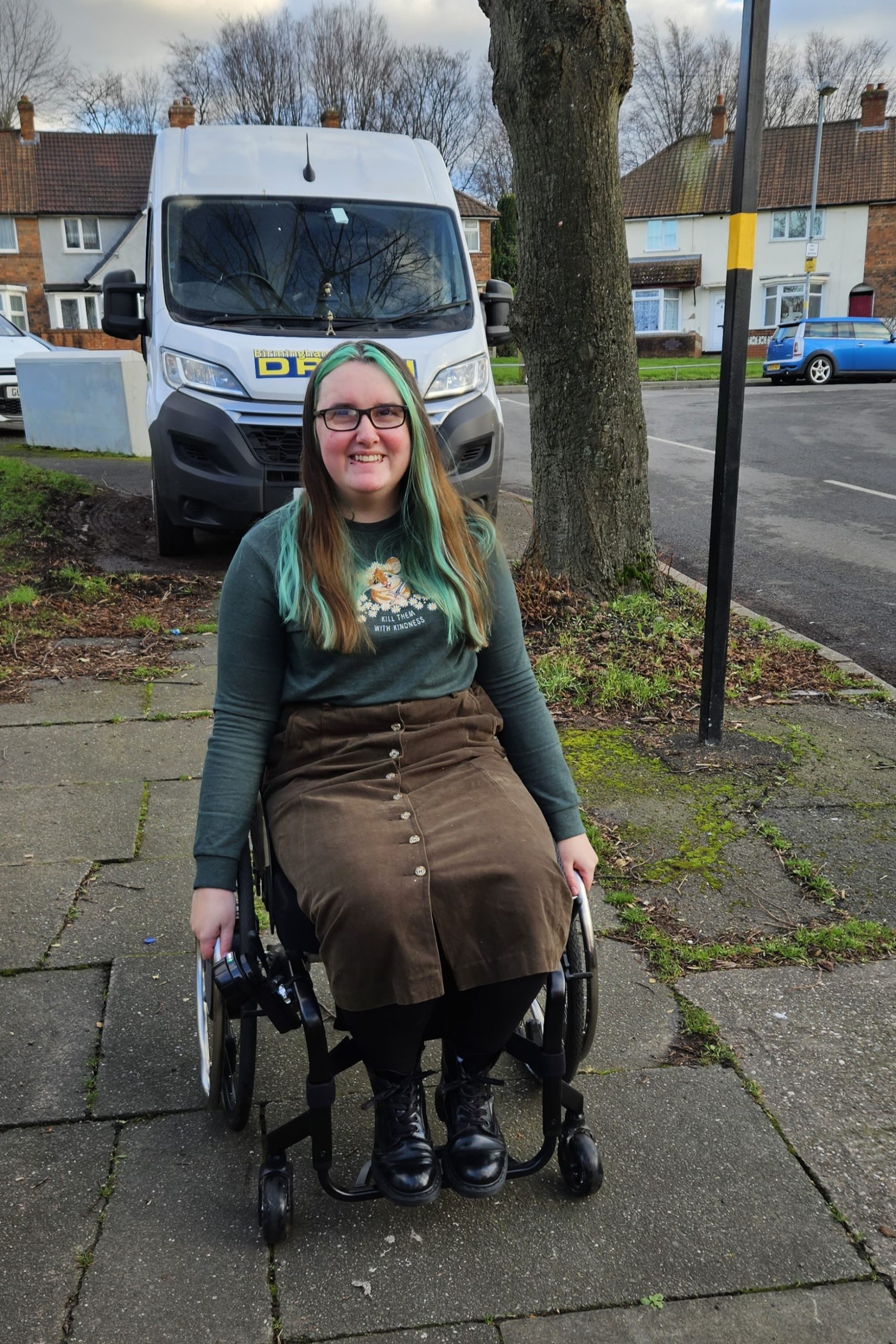 Rowan Stansfield, a partially sighted wheelchair user, is in front of a white transit van which has parked on the pavement making it difficult to pass.