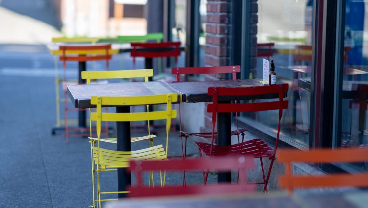 Red and yellow chairs placed on either side of a table outside a cafe.