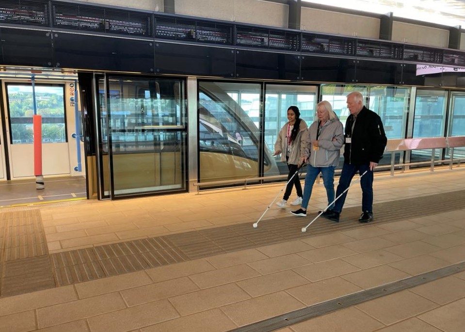 Bedfordshire SLC members using tactile markings on the platform, whilst walking alongside the DART Shuttle train.