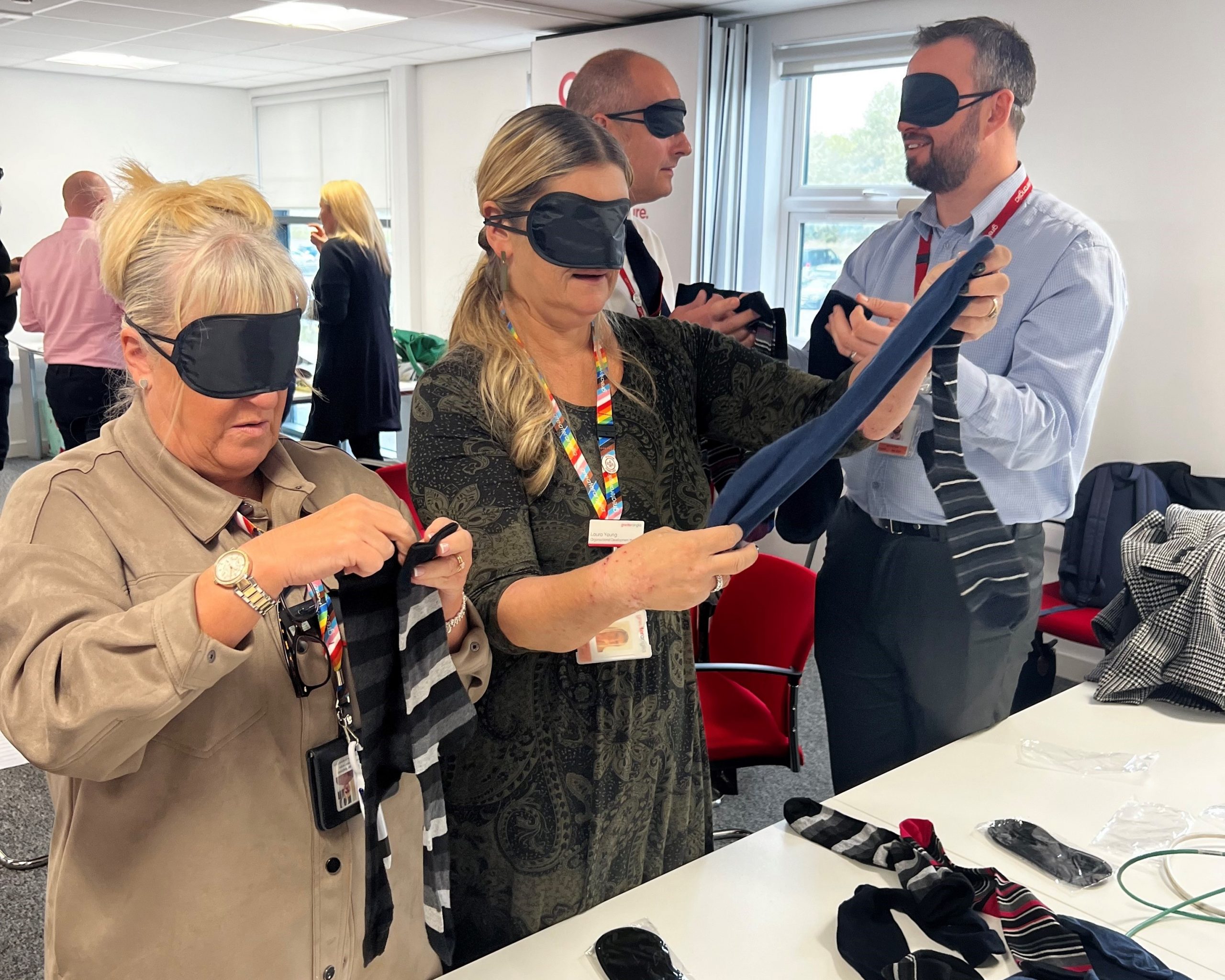 Greater Anglia staff members stood at a table, wearing black blindfolds, and trying to pair odd socks up.