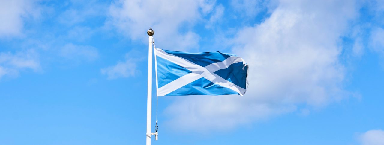 The Scottish flag bellowing in the wind, against blue sky.