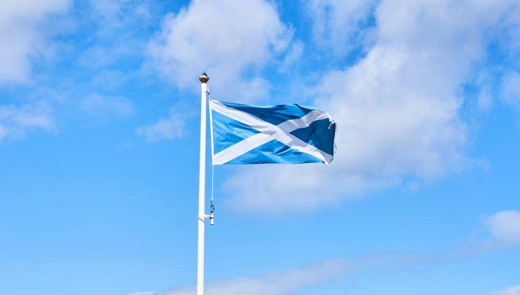 The Scottish flag bellowing in the wind, against blue sky.