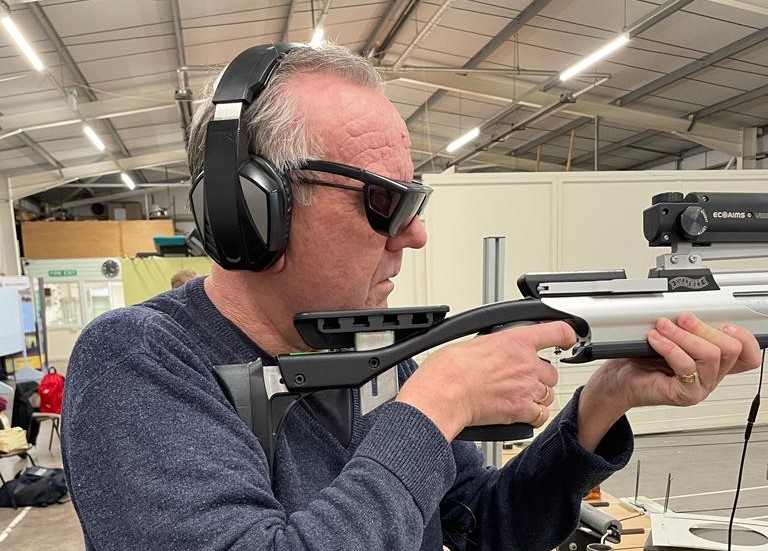Michael Parkinson - Lancashire SLC member, at a shooting range. The photo is taken from the side, and Michael is aiming his shot.