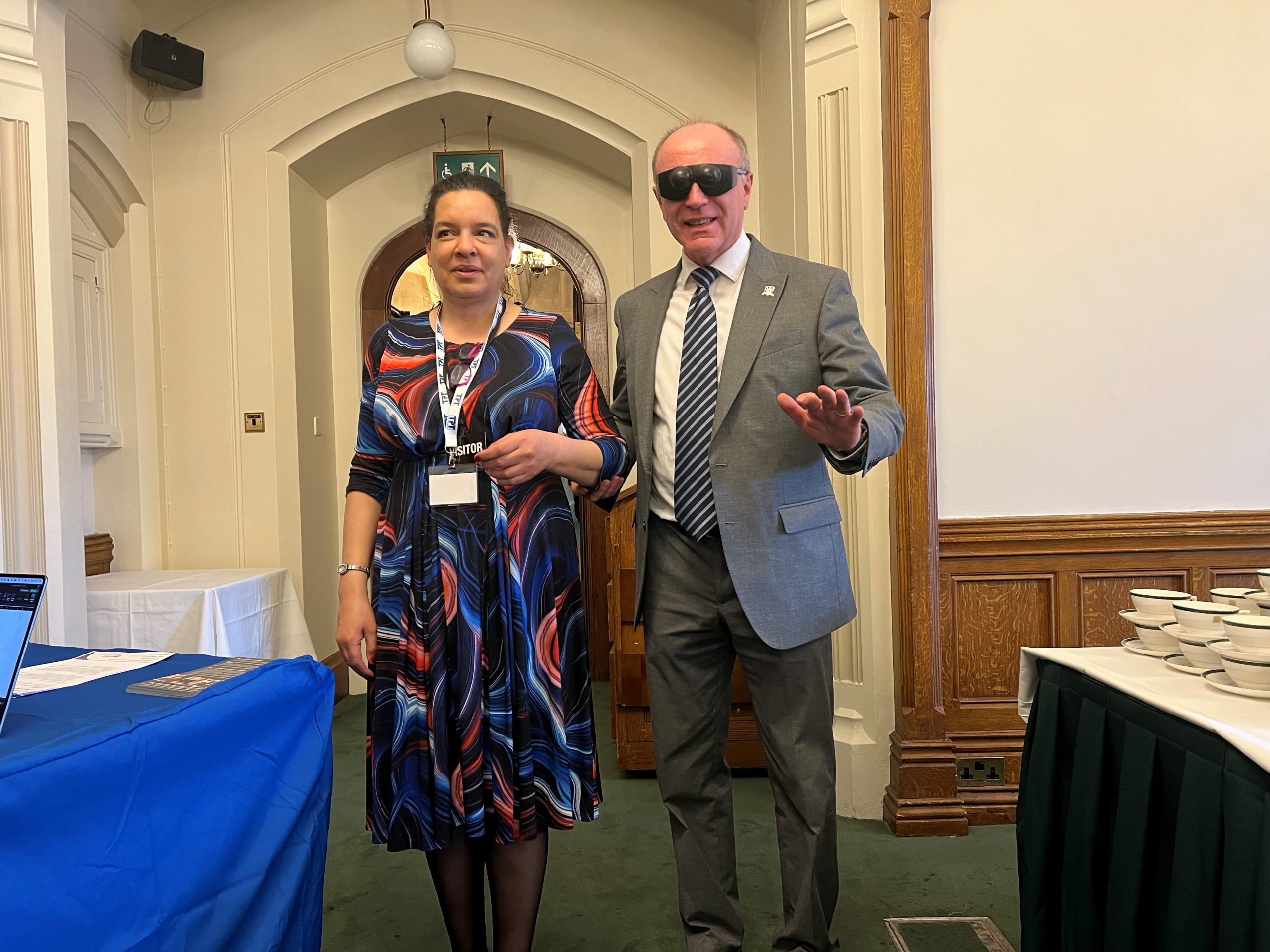 Denise, South East London SLC member, with Marco Di Longhi, MP for Dudley. Marco is wearing sim specs and being guided by Denise.