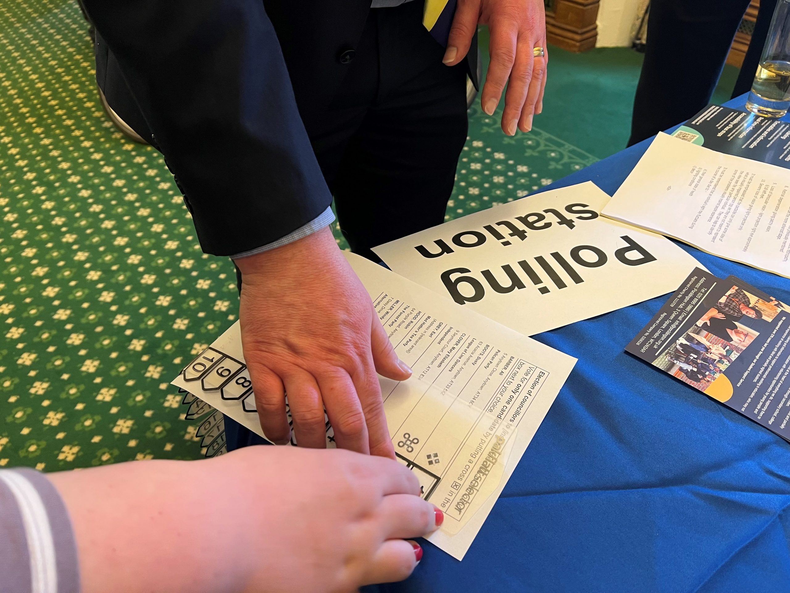 A close up image of Peter Gibson, MP,'s hand, using a McGonagle Reader in an accessible voting demonstration.