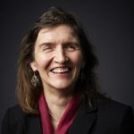 Headshot of Anna Lawson, West Yorkshire SLC member. Anna is stood against a black background and wearing a maroon shirt. She is smiling broadly at the camera.