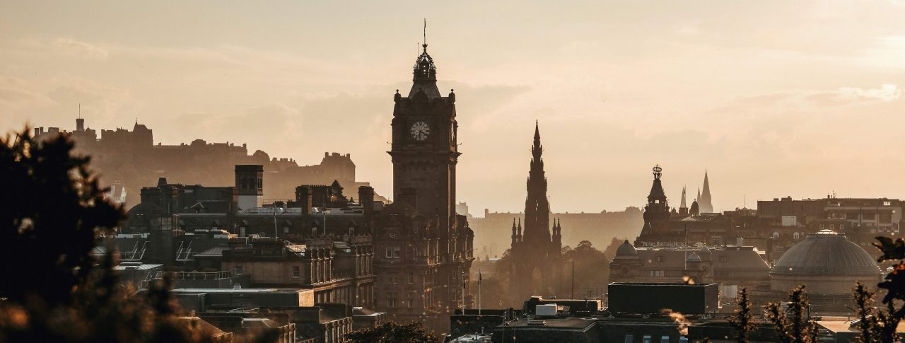 Looking across the skyline of Edinburgh, towards a clock tower at dusk.
