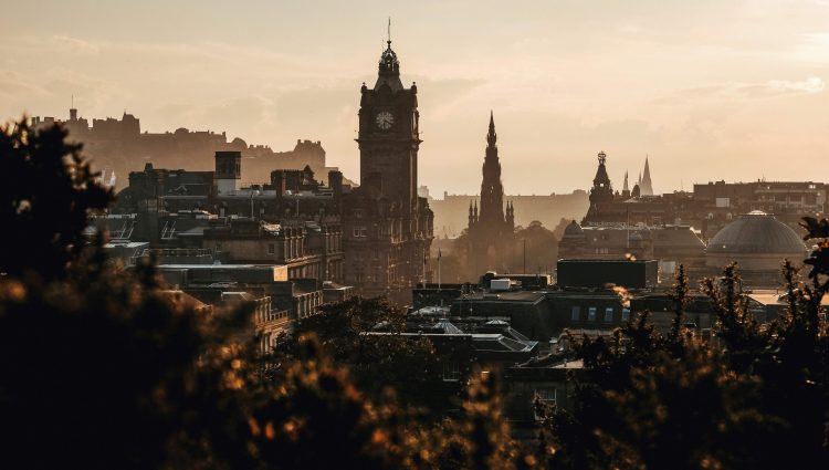 Looking across the skyline of Edinburgh, towards a clock tower at dusk.