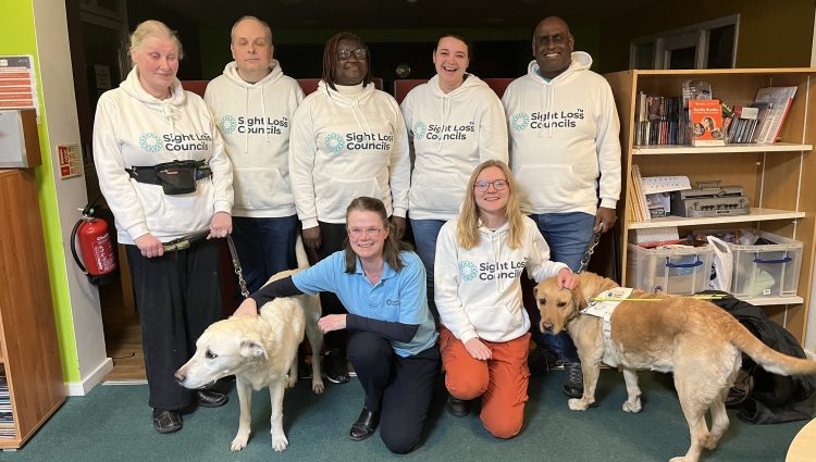 Sight Loss Council volunteers and staff pictured at their first anniversary. They are smiling at the camera and wearing Sight Loss Council hoodies.