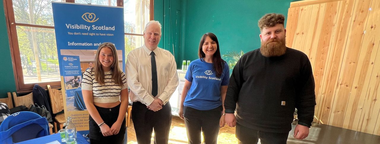 Photo taken at the launch event of Sight Loss Councils Scotland. From left to right: Lara, SLC volunteer, Iain Mitchell, Senior Engagement Manager for Sight Loss Councils North, Emma Scott, Head of Operations, Visibility Scotland, and Callum Lancashire, Engagement Manager for Sight Loss Councils Scotland. They are stood together next to a Visibility Scotland banner, smiling at the camera.