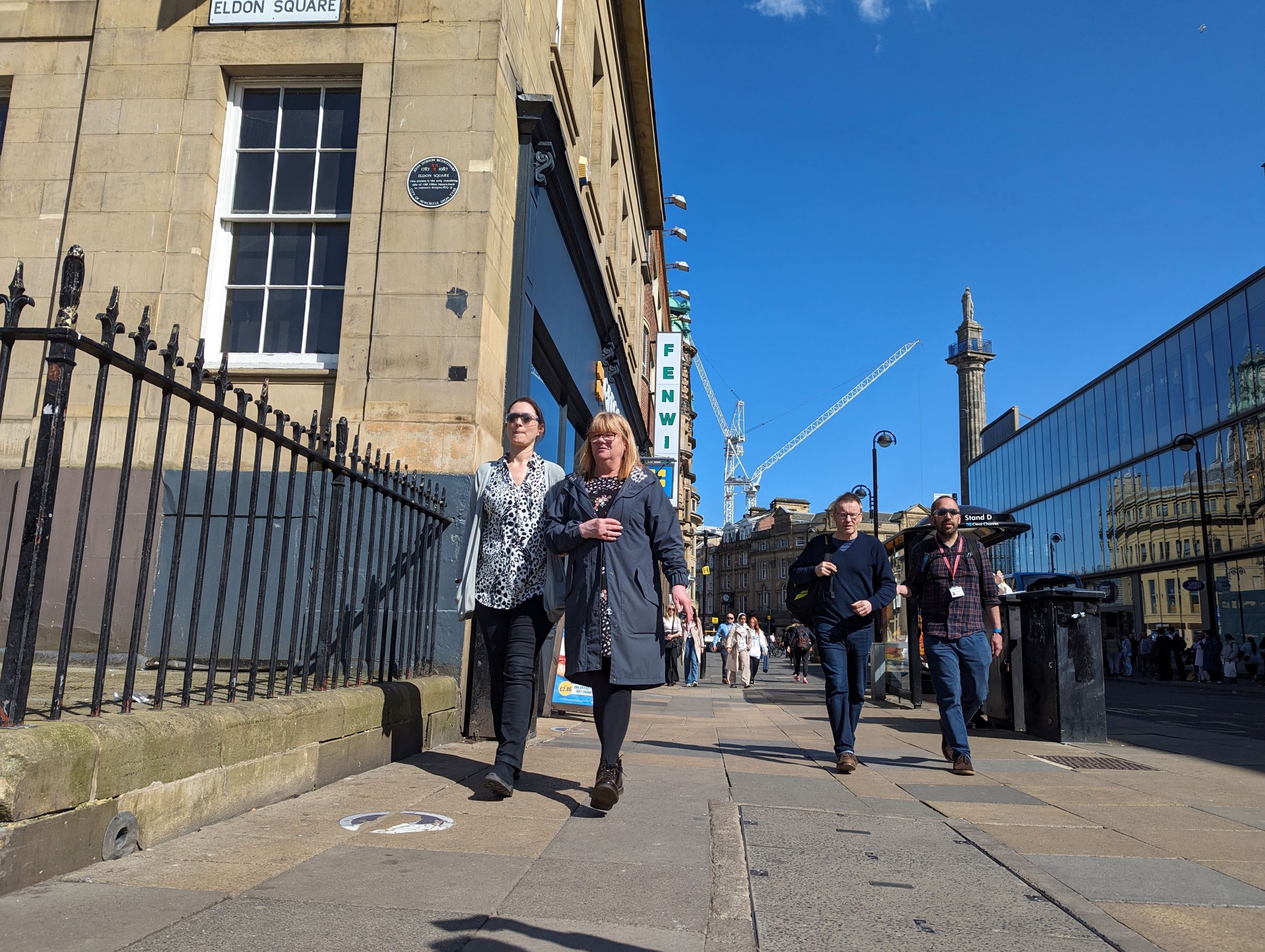 Officers from Newcastle City Council, during the sim spec walk. They are walking down the street in pairs, one in simulation glasses, the other guiding.