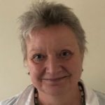 Photo of Maggie Anguish, Nottinghamshire SLC member. Maggie has short, grey hair and is wearing a white shirt and beaded necklace. She is smiling at the camera.
