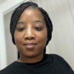 Michaela Hughes headshot. Michaela is wearing a black top and is smiling at the camera.