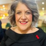 Helen Murphy headshot. Helen has silver curly hair and wearing a black top. She is smiling at the camera.