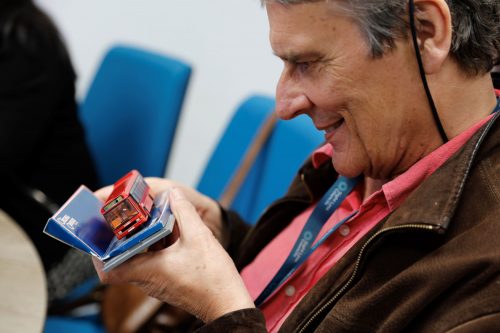A volunteer holding a tactile model of a red bus in a transport workshop about our new bus driver awareness training.